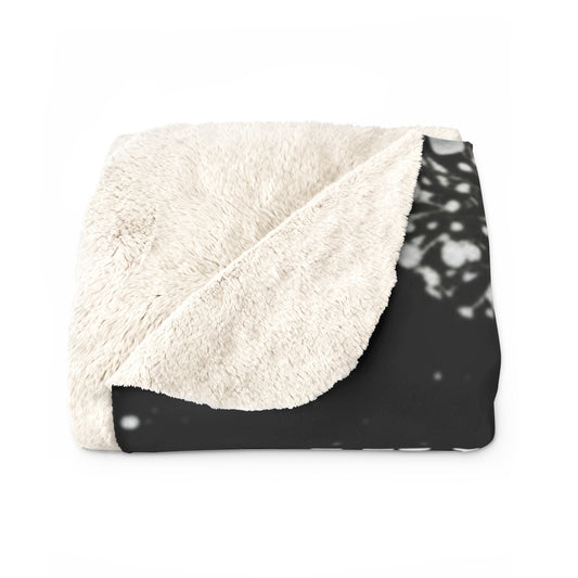 Folded blanket with white sherpa side and black patterned side on a white background